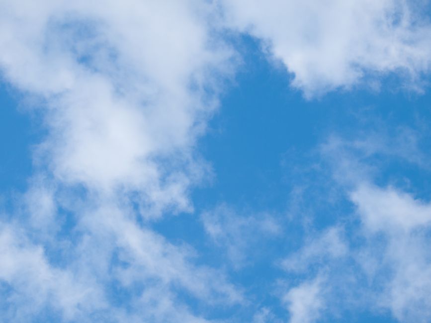 Clear blue sky with scattered fluffy white clouds. Perfect for nature or weather-related themes.