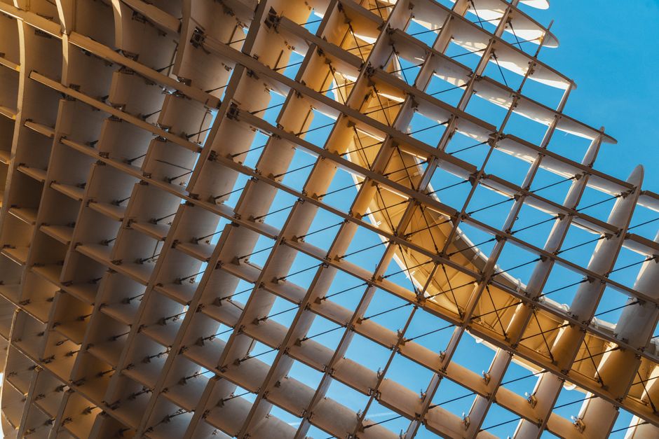 Abstract view of the Metropol Parasol in Seville featuring unique wooden design against a clear blue sky.