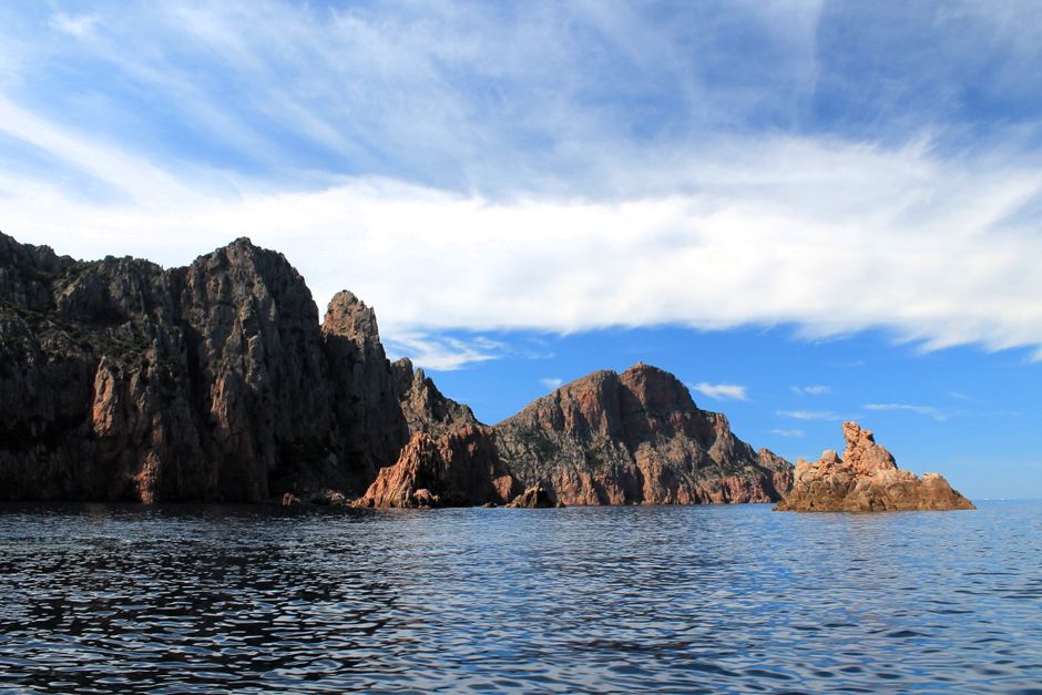 Scandola Nature Reserve's rugged cliffs meet the Mediterranean Sea on a sunny day.
