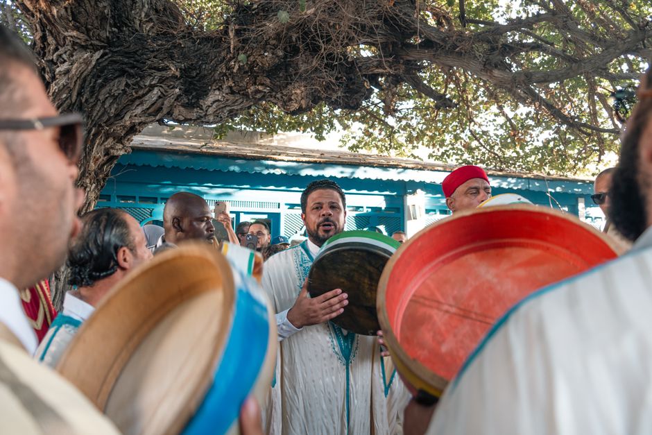 A vibrant gathering of men playing percussion in a rural Tunisian village ceremony.