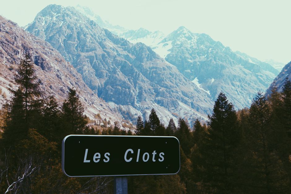 Breathtaking view of mountains and trees with a Les Clots sign in Champoléon, France.