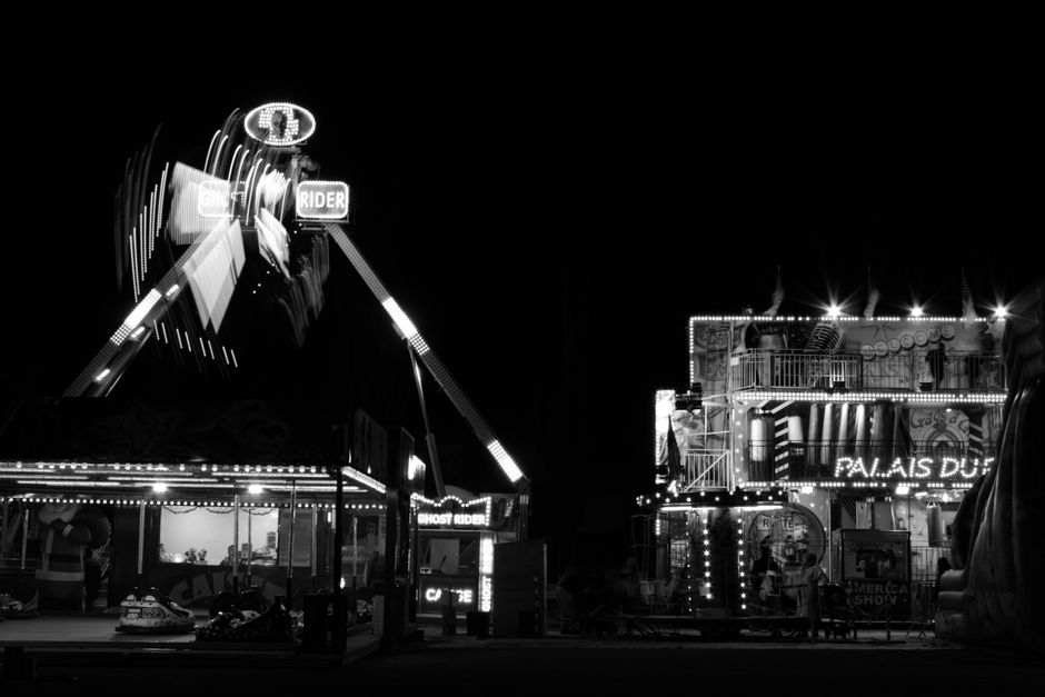 A vibrant night scene of a fairground ride in Villefranche-sur-Saône, France.