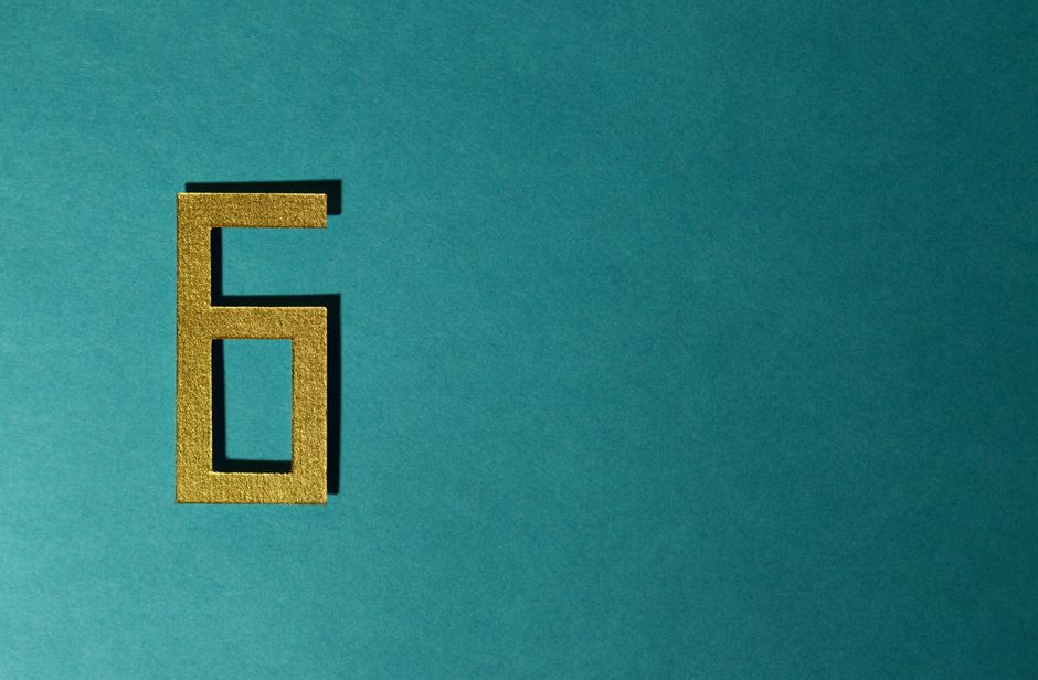 A golden number six on a teal background, perfect for decorative purposes.