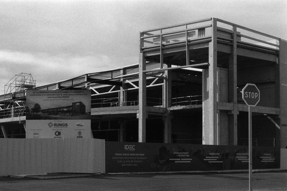 Monochrome image of a construction site in Rungis, France featuring a stop sign and building framework.