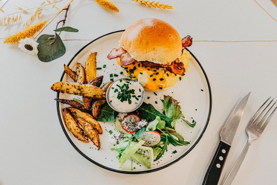 A gourmet burger with seasoned fries and fresh salad, perfect for food photography.