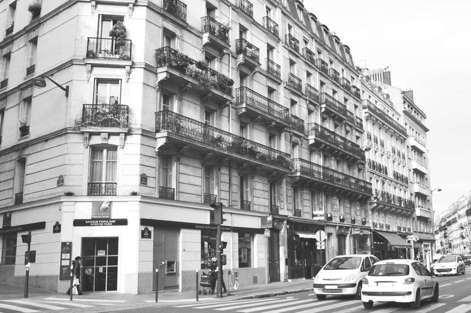Charming black and white photo of a Paris street capturing classic architecture and urban life.