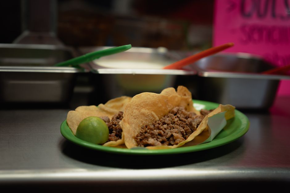 Close-up of delicious tacos with meat and lime, served on a green plate in a Mexican eatery.