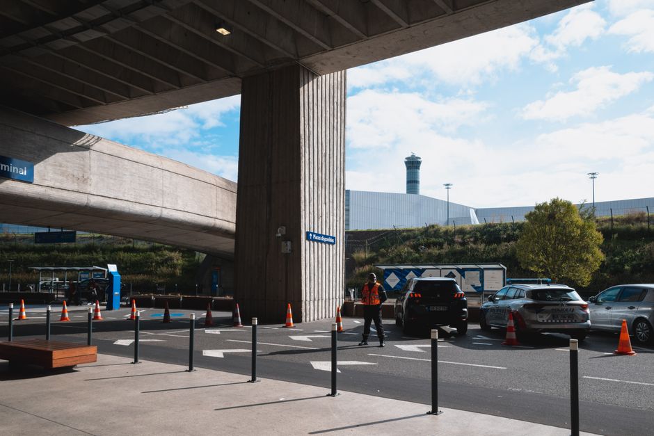 A bustling airport entrance with vehicles and people in Roissy, France.
