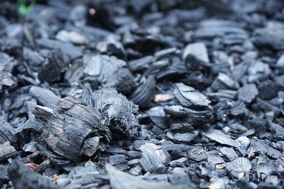 Detailed close-up of rough charcoal pieces spread outdoors, showcasing texture.