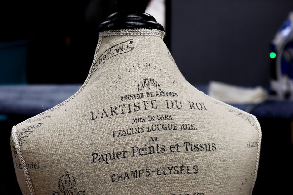 Back view of a vintage French mannequin with artistic text in a dark room.