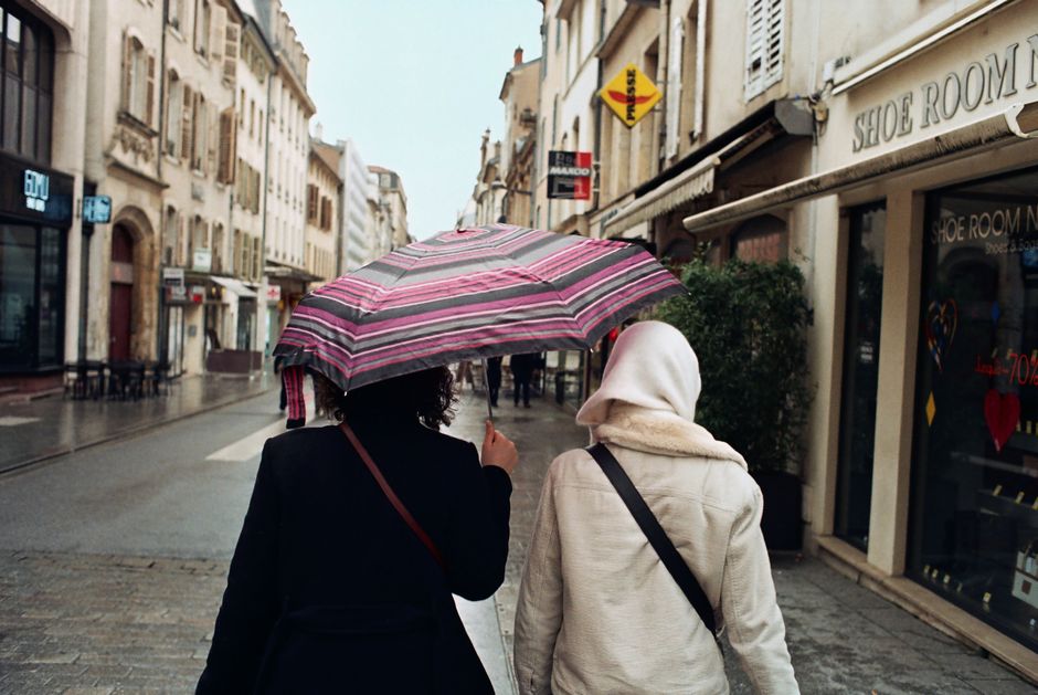 Two women walking under an umbrella in Nancy, France. Rainy day cityscape.