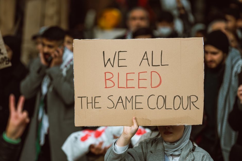 A person holding a protest sign emphasizing unity and equality during a rally.