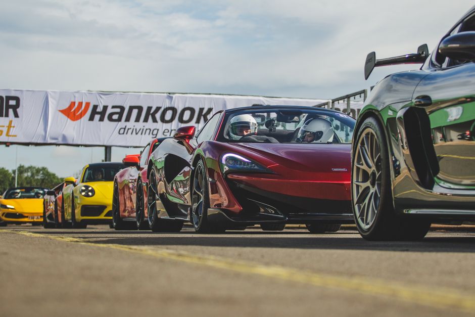 A lineup of high-performance sports cars ready for a racing event at a circuit.