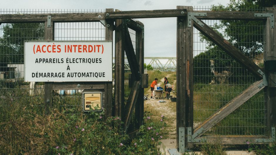 An open gate with a restricted access sign, two people visible beyond.