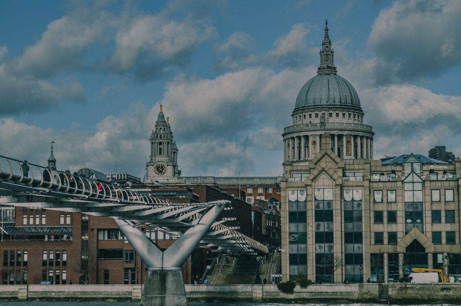 View of St Paul's Cathedral and Millennium Bridge on a cloudy day in London.