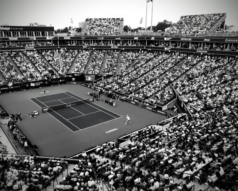 A black and white photo capturing a thrilling tennis match in a crowded outdoor stadium.