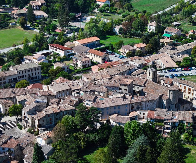 Explore the charming terracotta rooftops and lush greenery of Annot, a picturesque village in Provence, France, captured from above.