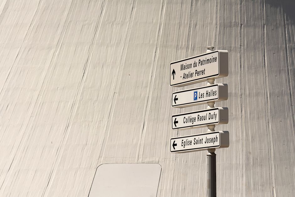 Directional signs in a cityscape setting with modern architectural backdrop.