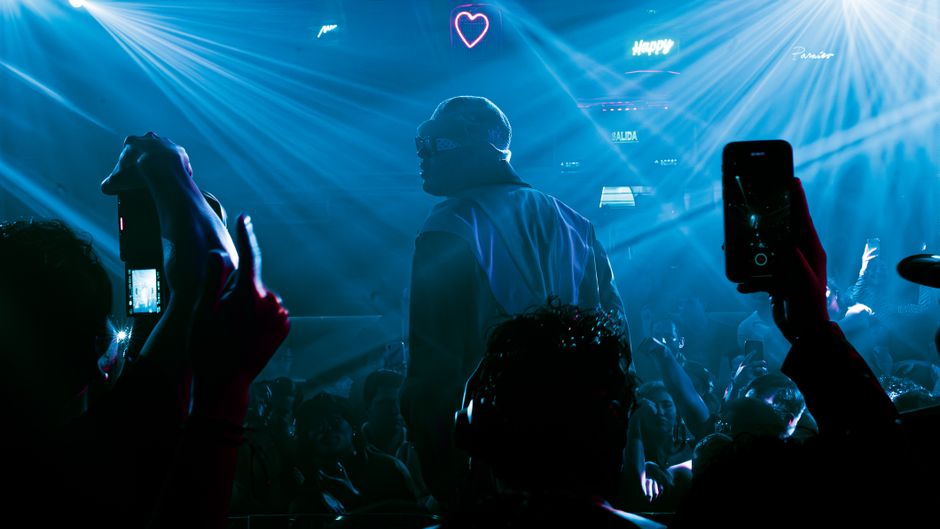 Vibrant nightclub scene in Mexico City with DJ performing. Blue laser lights create a dynamic atmosphere.