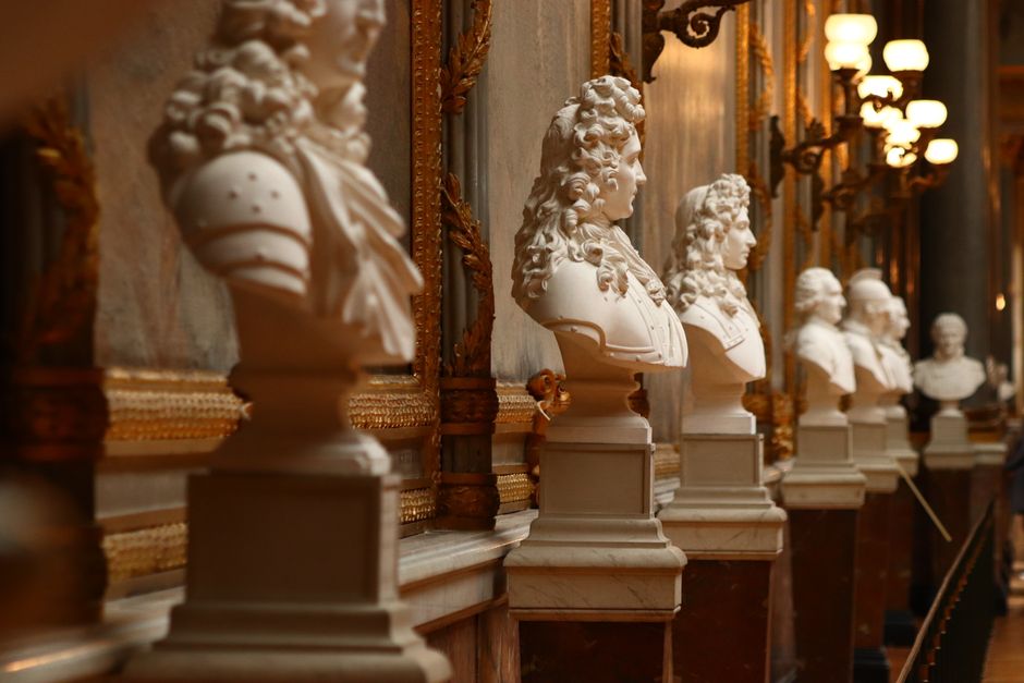 Row of marble busts in a grand hallway at the Palace of Versailles, France.