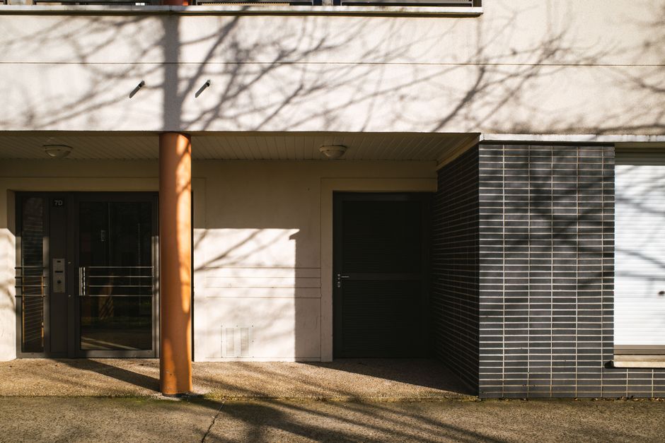 Entrance of a modern apartment building with distinctive shadows in Compiègne, Hauts-de-France, France.