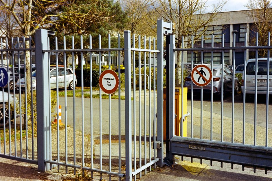 Metal gate in Compiègne, France featuring traffic control signs. Urban setting, daytime.
