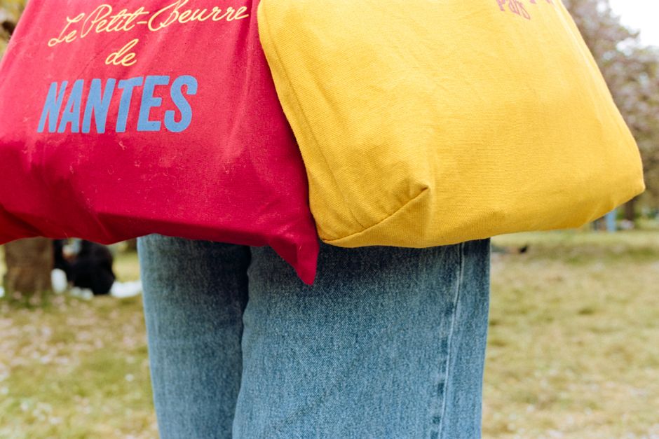 Vibrant tote bags with Nantes text in a park setting during springtime.