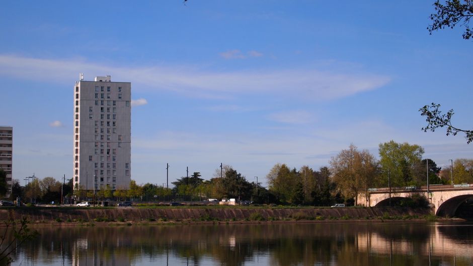 A serene view of a tower and bridge reflecting in the Loire River in Nantes, France.