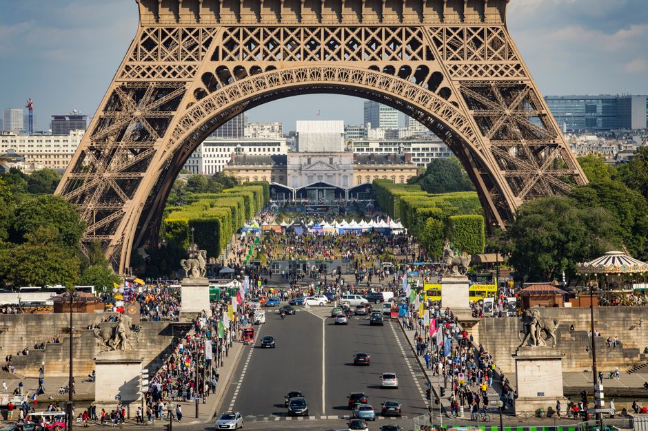 Eiffel Tower framing a bustling street scene in Paris with vibrant activity and landmarks.