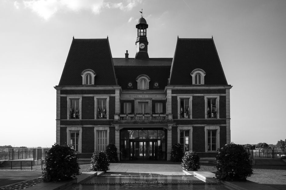 Elegant black and white photo of a classic French town hall with symmetrical architecture.