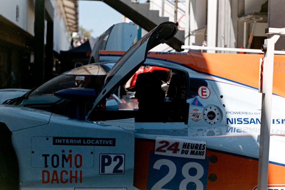 Close-up of a racing car at Le Mans with open doors, showcasing sponsorship and car number.