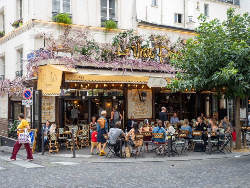 Outdoor view of Le Vrai Paris bistro in Montmartre, Paris, with people dining and vibrant atmosphere.