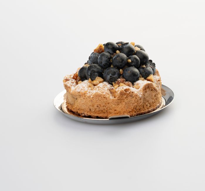 Mouthwatering blueberry tart with powdered sugar on a minimalist white backdrop.