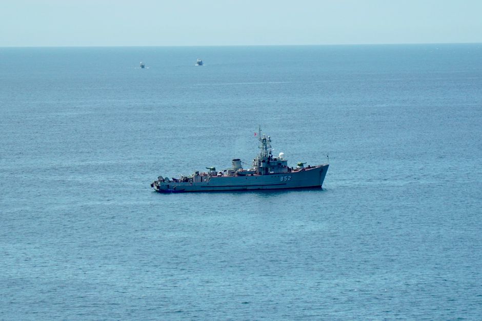 A military ship navigating the calm blue ocean under a clear sky, showcasing nautical power.