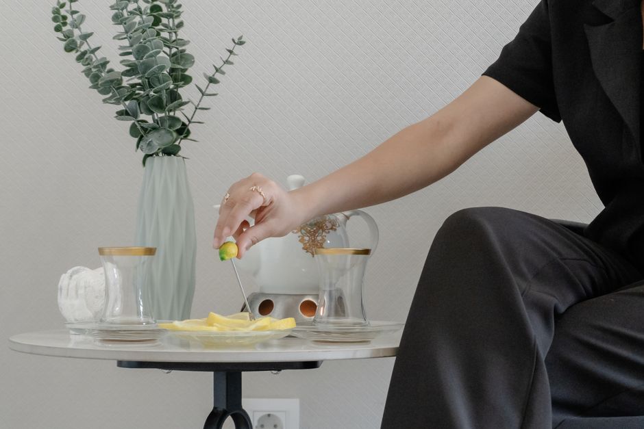 Stylish indoor tea setup with eucalyptus vase, served with lemon slices and a modern teapot.