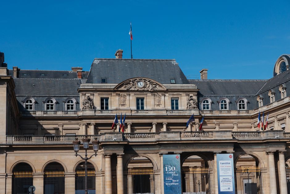 Front view of the Palais Royal in Paris, showcasing French architecture and flags.
