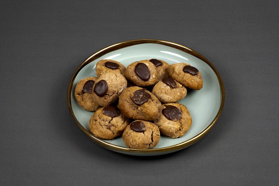 A plate of freshly baked chocolate cookies with melted chocolate, perfect for dessert lovers.