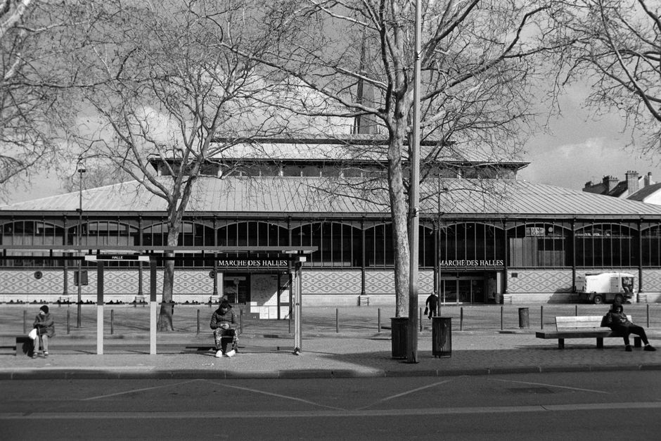 Black and white photo of Marché des Halles in Troyes, France, with people sitting and walking.