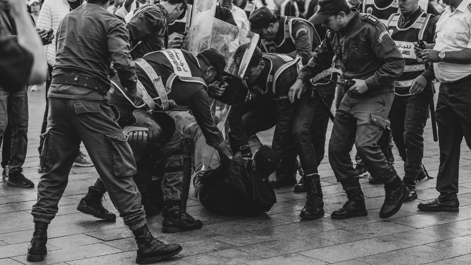 A group of police officers detaining a protester during a demonstration in Rabat, Morocco.