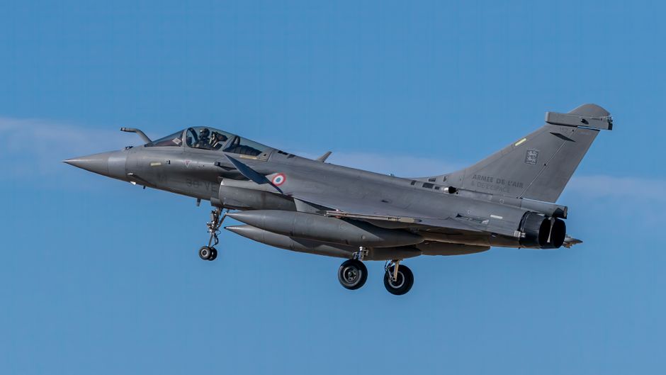A French Rafale fighter jet flying under a clear blue sky in Los Llanos, Spain.