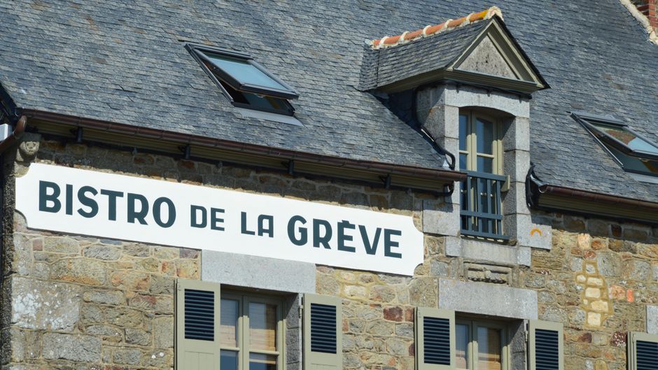 Rustic stone bistro facade with French signage in Saint-Suliac, Brittany, France.