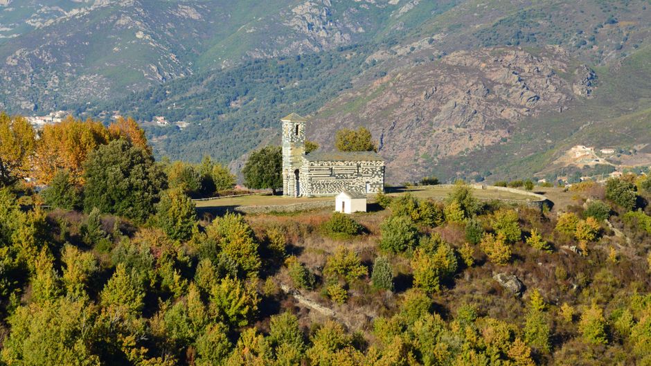 Aerial view of the historic San Michele di Murato church surrounded by lush greenery in Corse, France.