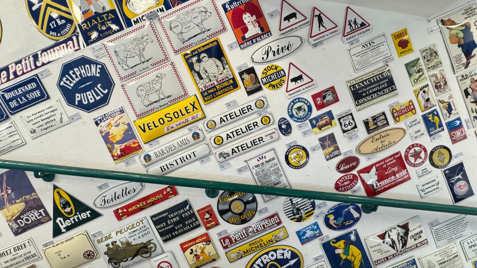 A collage of colorful vintage French advertising signs displayed on a wall.