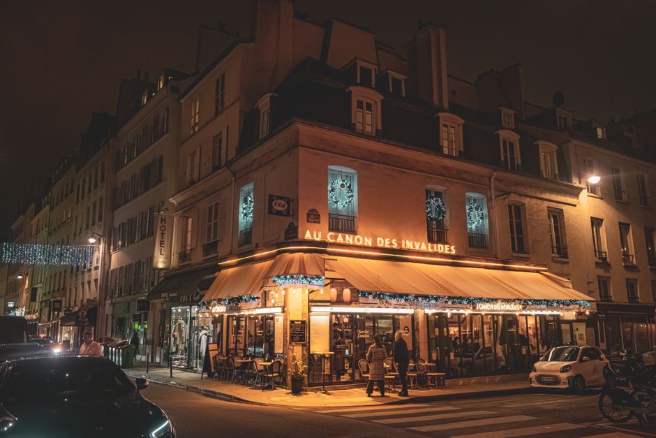Cozy evening scene at a Parisian cafe with warm lights and decor.