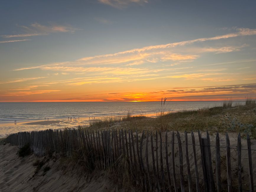 Serene sunset over a sandy beach and wooden fence at La Tranche-sur-Mer, France.