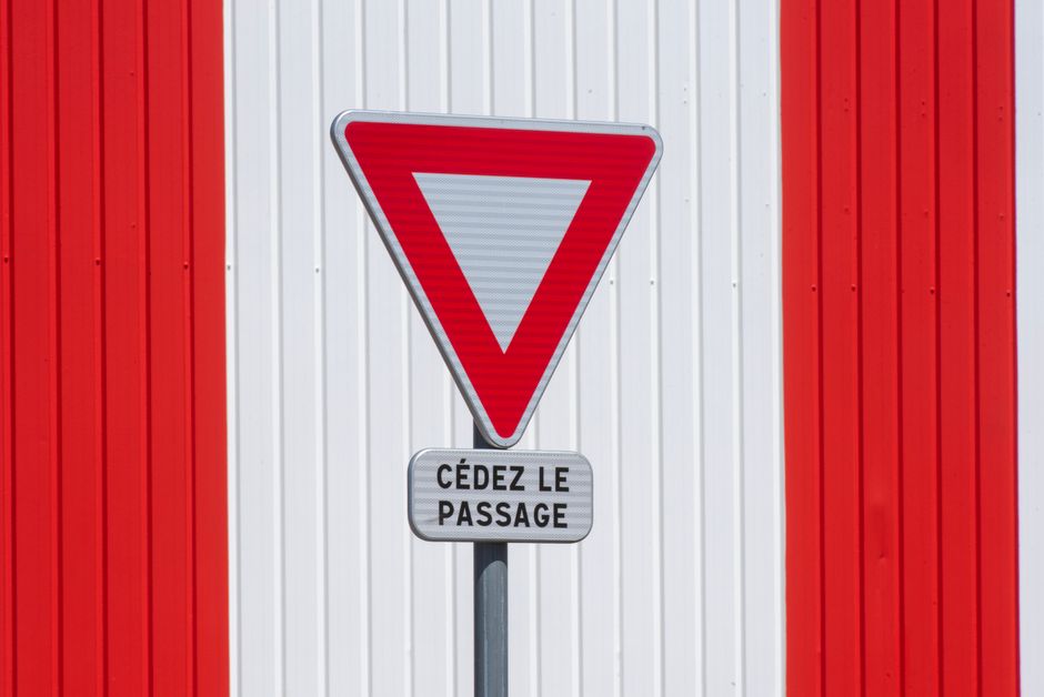 Yield sign with 'Cédez le passage' text on red and white striped background.