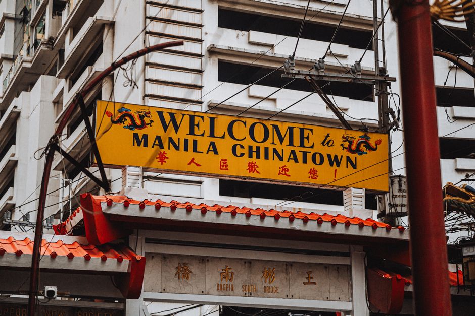 Bright yellow welcome sign at historic Manila Chinatown, featuring traditional architectural elements.