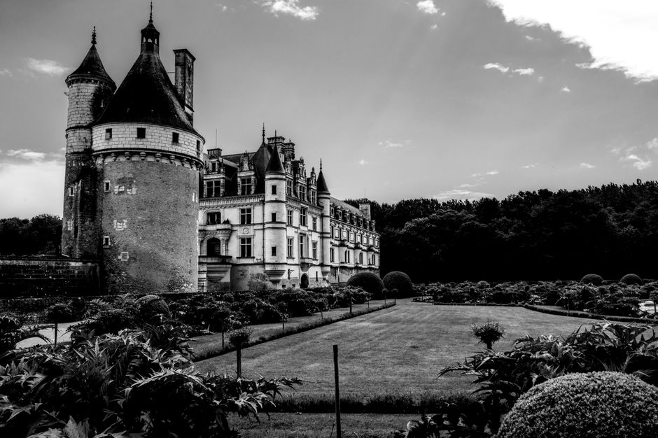 Elegant black and white photo of Château de Chenonceau with garden view in France.