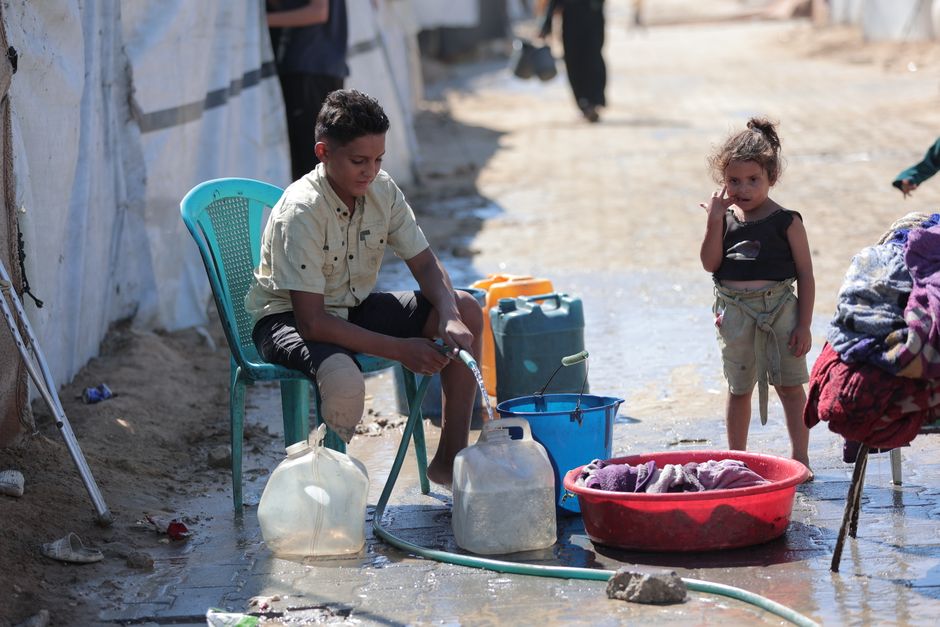 Child collecting water in a refugee camp setting, highlighting daily challenges.