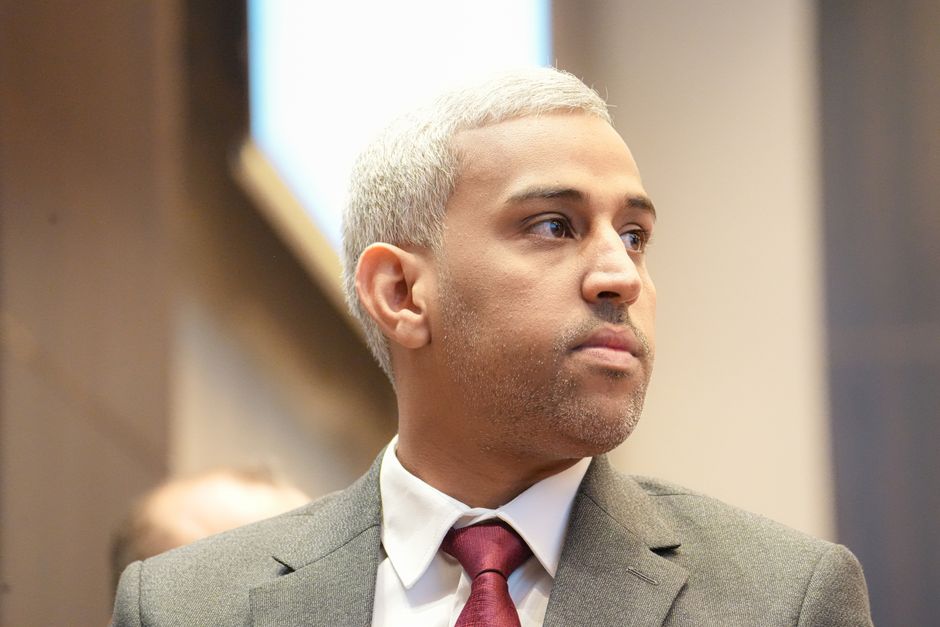Confident businessman with gray hair in a suit and red tie, looking thoughtful.
